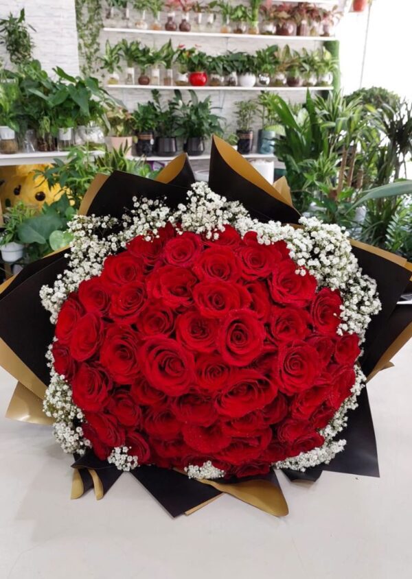 100 red rose bouquet with fresh vibrant roses, accented with baby's breath and wrapped in black and gold paper, perfect for romantic occasions and available for delivery in Dubai and Sharjah.