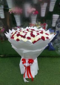 Elegant luxury bouquet with red and white roses and white chrysanthemums, beautifully wrapped with a red and white ribbon, perfect for gifting in Dubai.