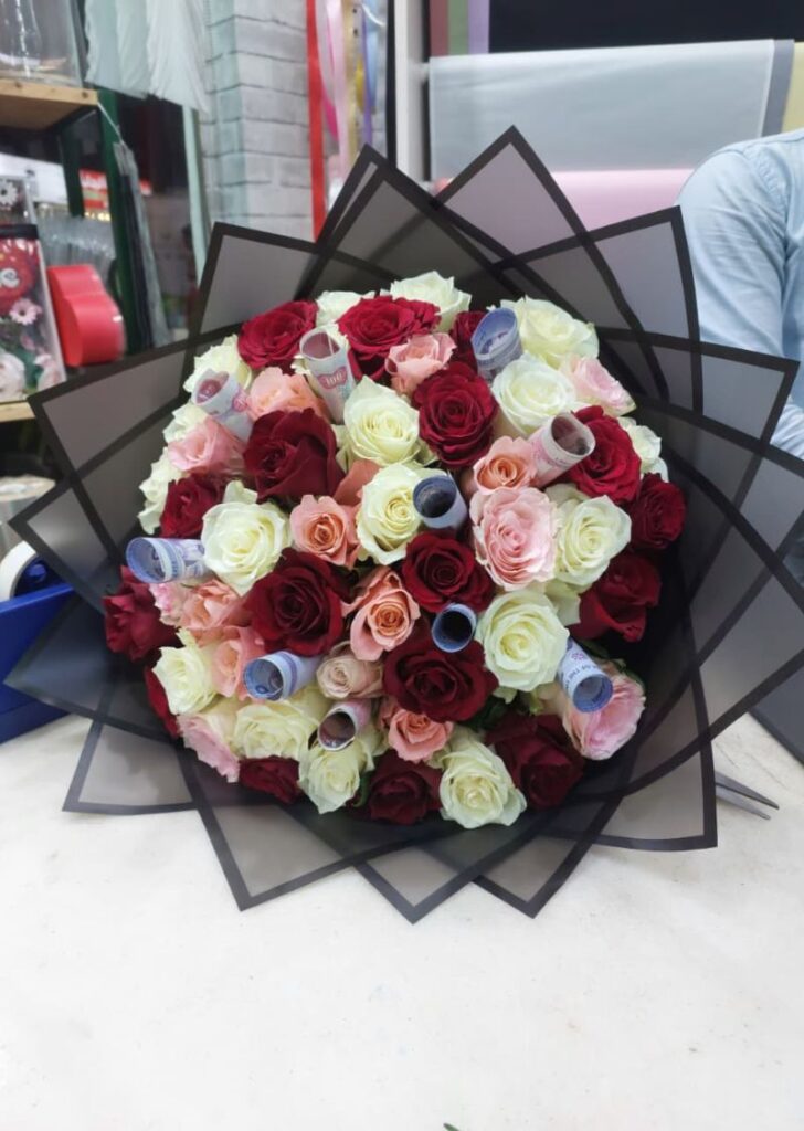Luxury bouquet of red, white, pink, and peach roses with rolled currency notes arranged as a premium gift in UAE.