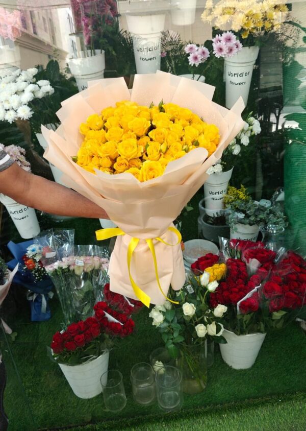A stunning bouquet of fresh yellow spray roses, also known as baby roses, beautifully wrapped and displayed outside a flower shop in Dubai.