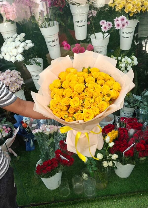 A stunning bouquet of fresh yellow spray roses, also known as baby roses, beautifully wrapped and displayed outside a flower shop in Dubai.