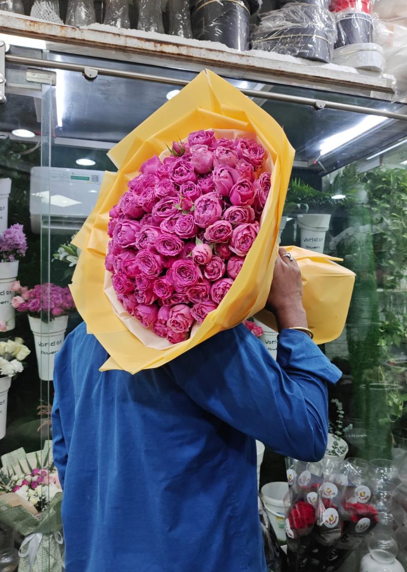 Vibrant mixed floral bouquet with premium pink roses wrapped in elegant yellow paper