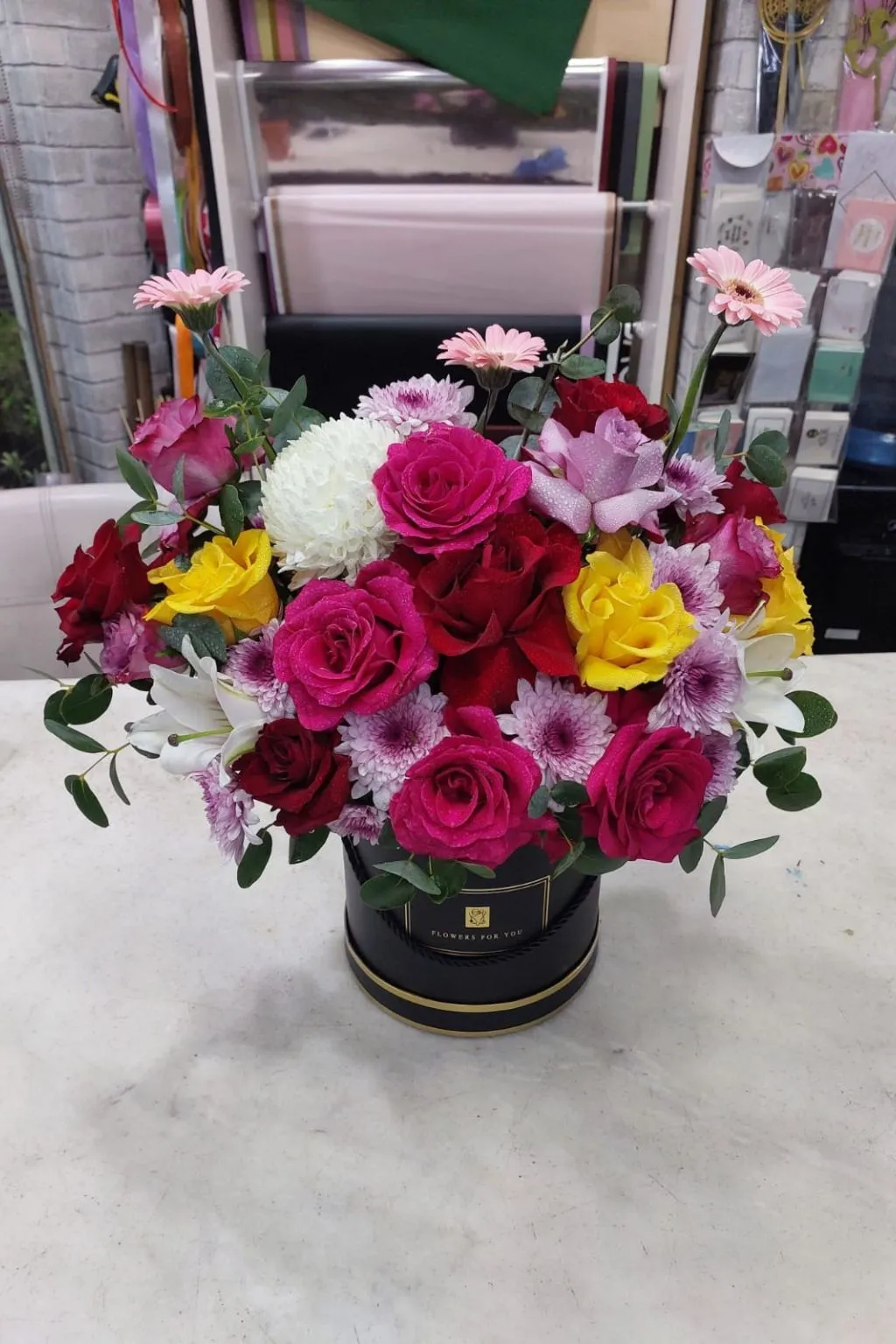 Close-up of gerbera daisies, lilies and roses in a mixed flower gift box