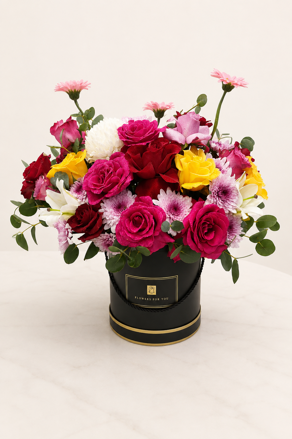 Mixed flower box with red, pink and yellow roses, chrysanthemums and gerberas in a black hat box