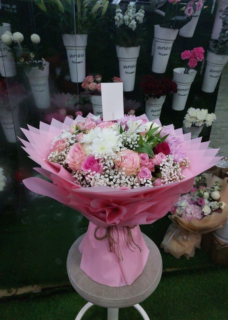 Luxury mixed flower bouquet with pink roses, chrysanthemums, and baby’s breath wrapped in elegant pink paper