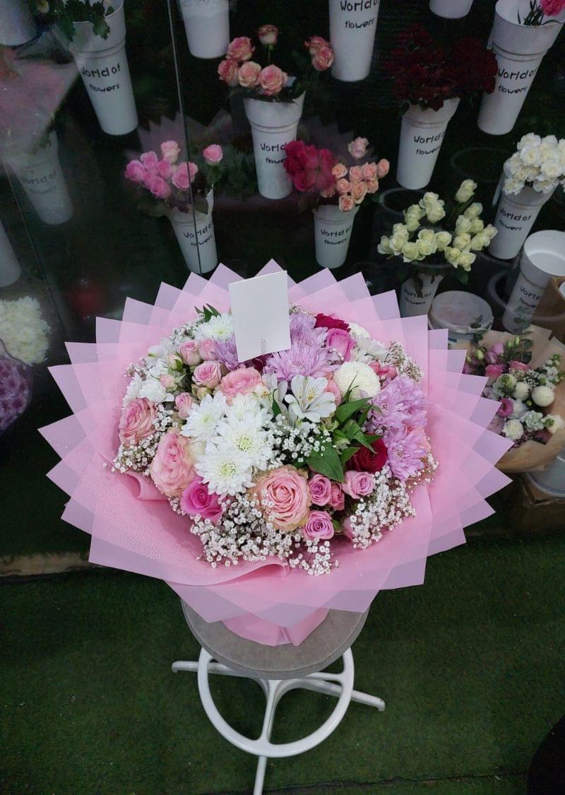 Luxury mixed flower bouquet with pink roses, chrysanthemums, and baby’s breath wrapped in elegant pink paper