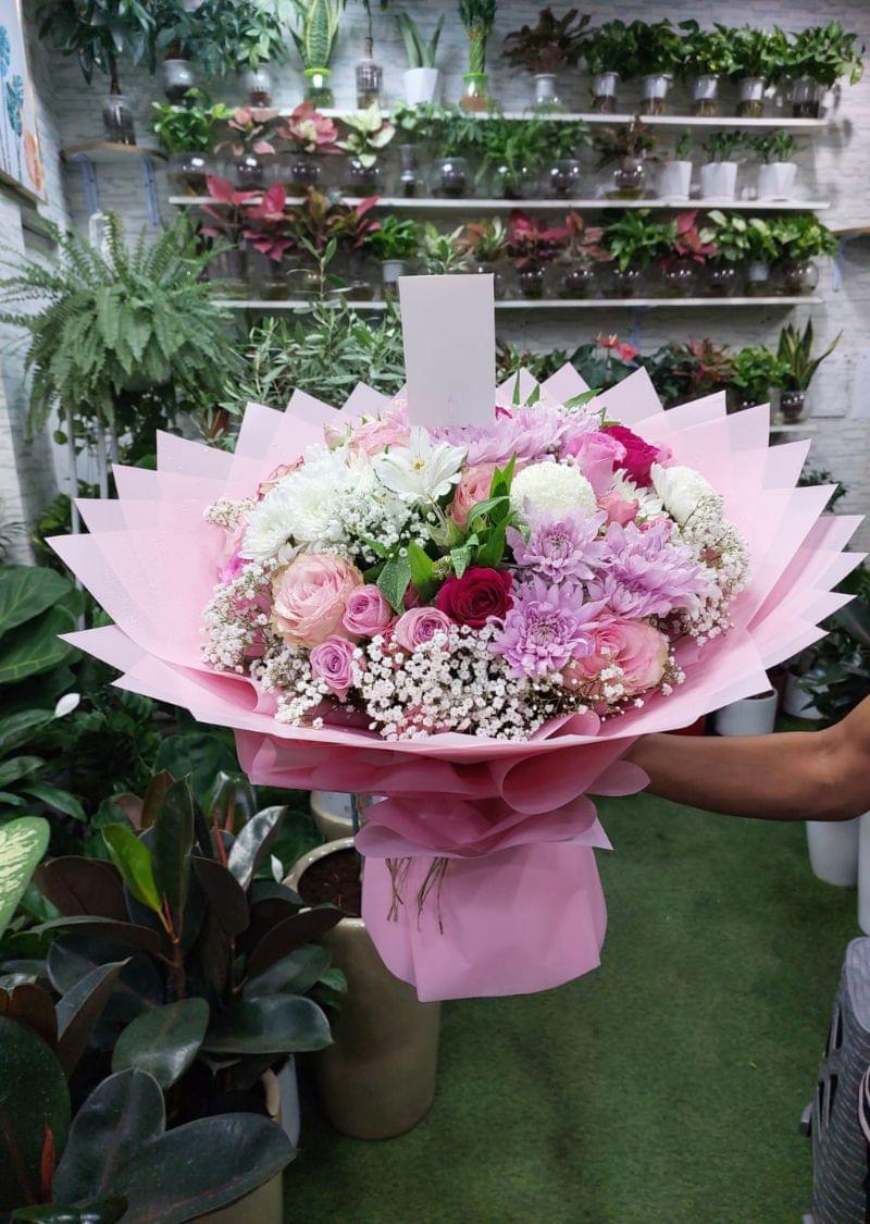 Luxury mixed flower bouquet with pink roses, chrysanthemums, and baby’s breath wrapped in elegant pink paper